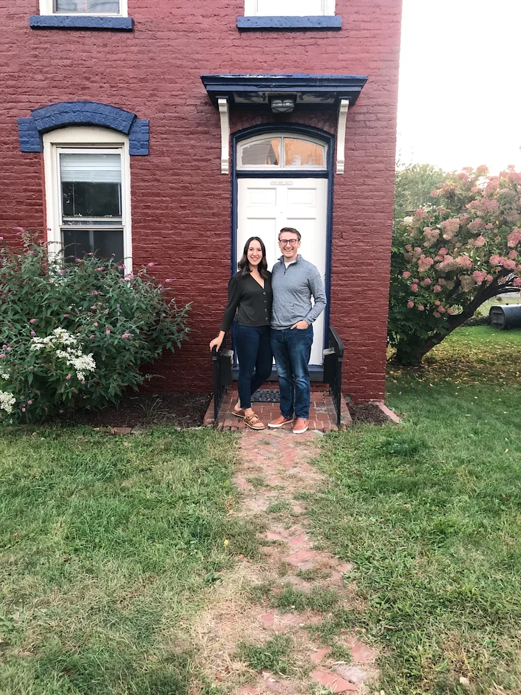 Ali and Josh standing outside a brick house, from their 2020 story